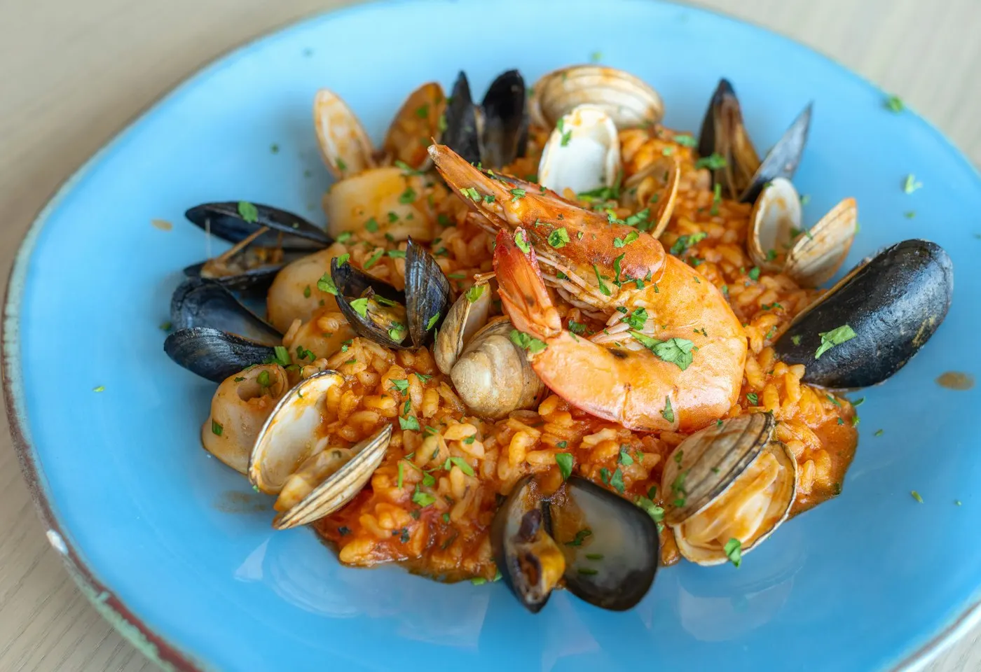 Arroz meloso con gambas, mejillones y almejas en plato azul